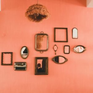 Vintage mirrors and lampshade on a stylish coral wall for eclectic interior design.